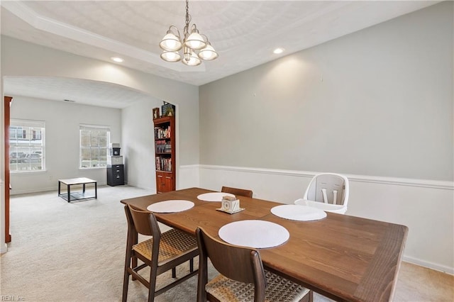 carpeted dining room featuring an inviting chandelier and a tray ceiling