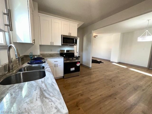 kitchen featuring sink, dark wood-type flooring, stainless steel appliances, light stone countertops, and white cabinets