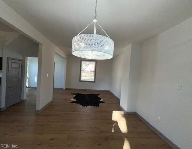 unfurnished dining area featuring dark hardwood / wood-style floors and a chandelier