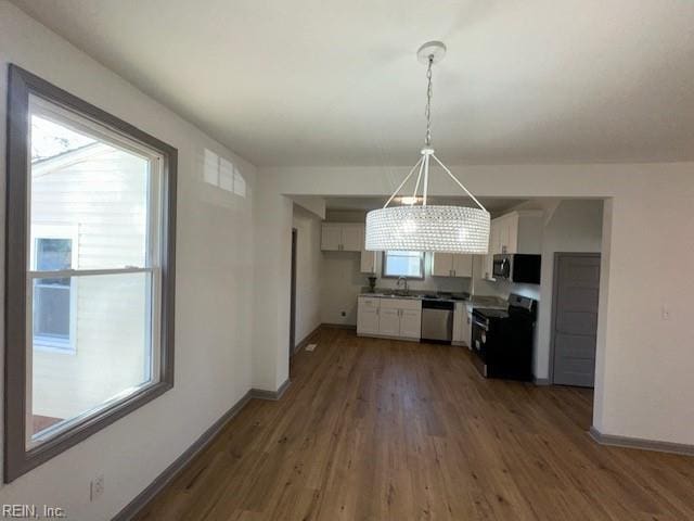 kitchen with white cabinetry, decorative light fixtures, a wealth of natural light, and appliances with stainless steel finishes