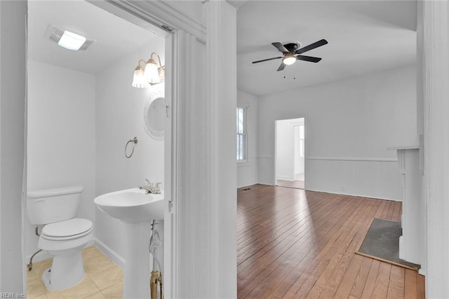 bathroom with hardwood / wood-style floors, toilet, and ceiling fan