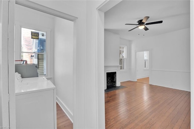 unfurnished living room featuring ceiling fan, washer and clothes dryer, and light hardwood / wood-style flooring