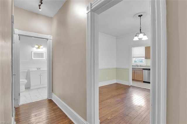 hall with ornamental molding, a chandelier, and light hardwood / wood-style flooring