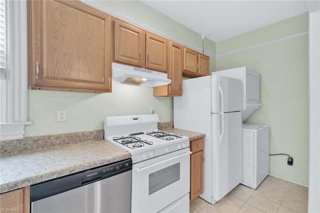 kitchen with stacked washer and clothes dryer, light tile patterned floors, and white appliances