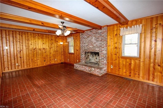 unfurnished living room with ceiling fan, a fireplace, beam ceiling, and wood walls