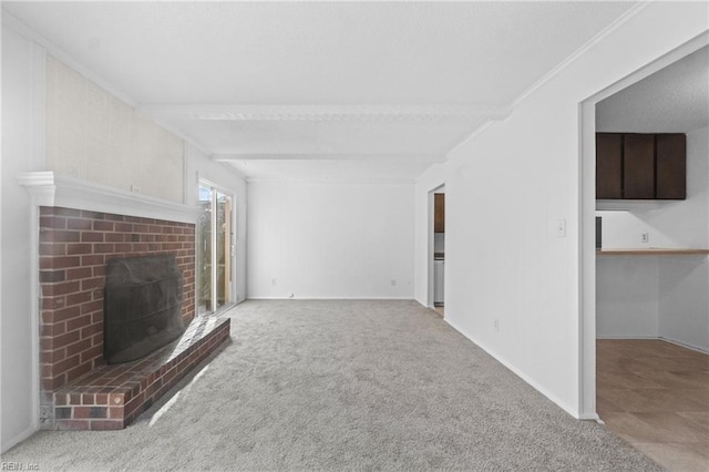 unfurnished living room with ornamental molding, beam ceiling, carpet floors, and a brick fireplace