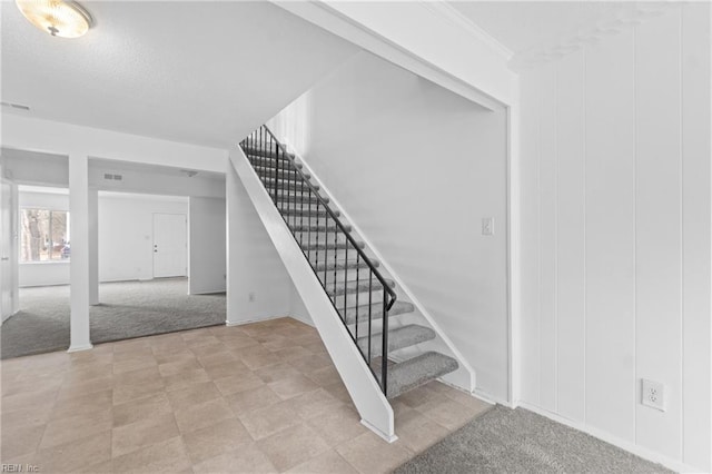 stairway with carpet floors and ornamental molding