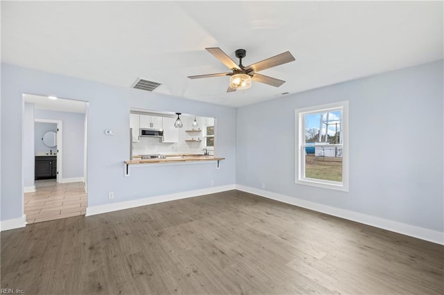 unfurnished living room featuring sink, ceiling fan, and light hardwood / wood-style flooring