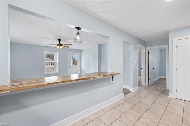 interior space featuring light tile patterned floors, wooden counters, and ceiling fan