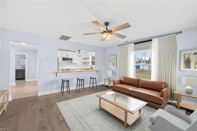 living room with ceiling fan, sink, and light hardwood / wood-style floors