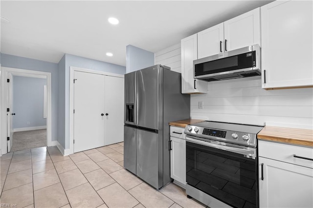 kitchen featuring wood counters, tasteful backsplash, light tile patterned floors, appliances with stainless steel finishes, and white cabinets