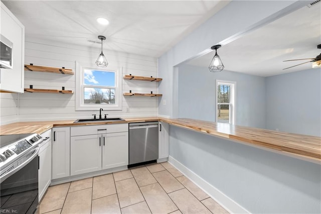 kitchen with appliances with stainless steel finishes, white cabinets, wood counters, and decorative light fixtures