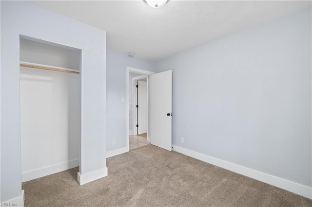 unfurnished bedroom featuring light carpet and a closet