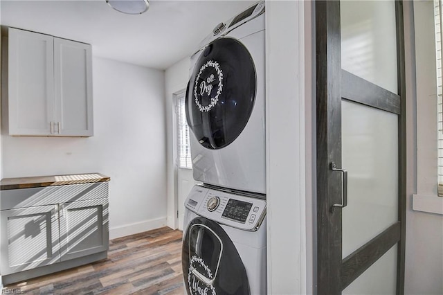 laundry room with stacked washer / drying machine and dark hardwood / wood-style floors