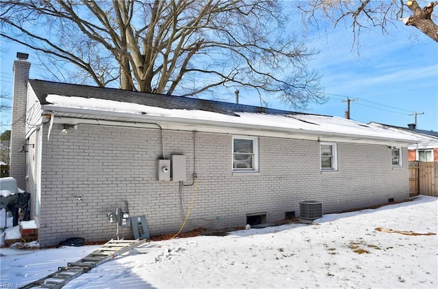 snow covered house featuring central AC