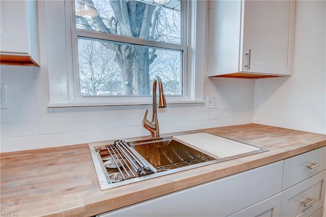 kitchen featuring white cabinetry, sink, and butcher block countertops