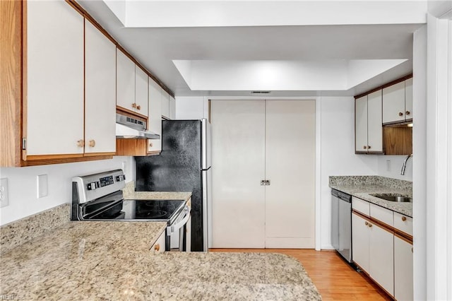 kitchen with sink, extractor fan, white cabinetry, light wood-type flooring, and appliances with stainless steel finishes