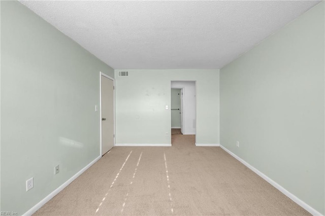 carpeted empty room featuring a textured ceiling