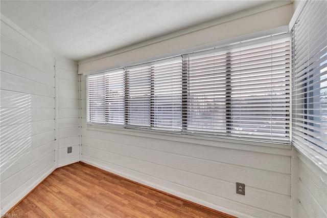 unfurnished room featuring wooden walls