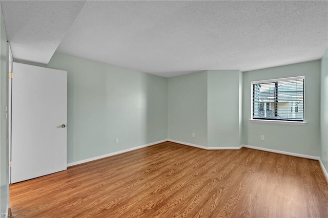 empty room with a textured ceiling and light wood-type flooring