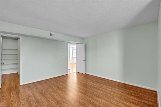 unfurnished room with light hardwood / wood-style floors and a textured ceiling