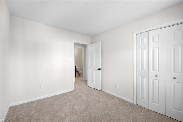 unfurnished bedroom with light colored carpet and a closet