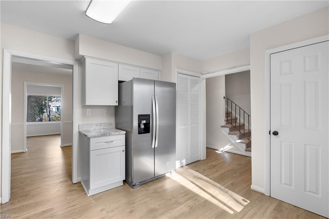 kitchen featuring white cabinetry, stainless steel fridge, light stone counters, and light wood-type flooring