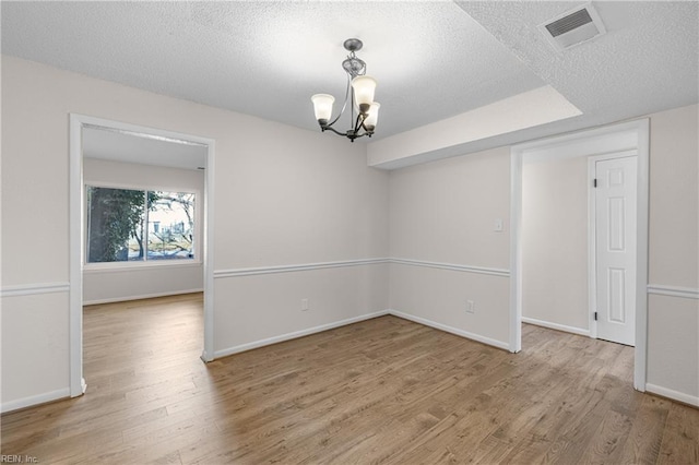 spare room featuring hardwood / wood-style flooring, a textured ceiling, and a notable chandelier