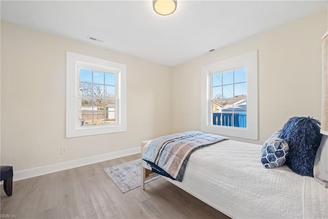 bedroom with hardwood / wood-style floors and multiple windows