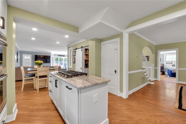 kitchen featuring light stone counters, a wealth of natural light, stainless steel gas cooktop, white cabinets, and a barn door