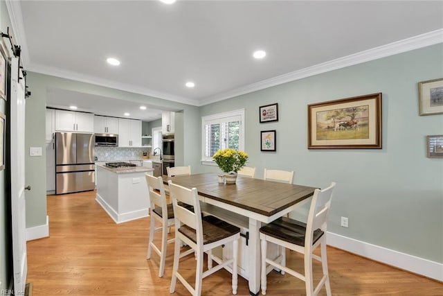 dining room featuring crown molding, a barn door, and light hardwood / wood-style floors