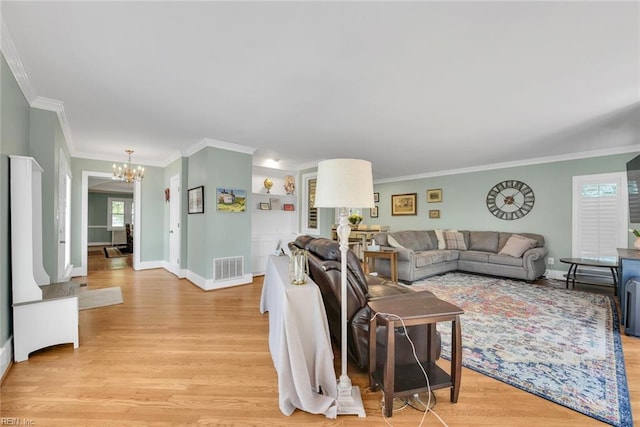 living room featuring an inviting chandelier, ornamental molding, and light wood-type flooring