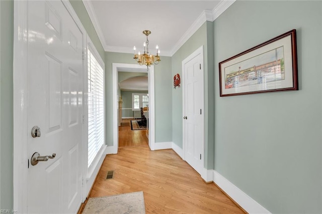 hallway featuring ornamental molding, a chandelier, and light wood-type flooring