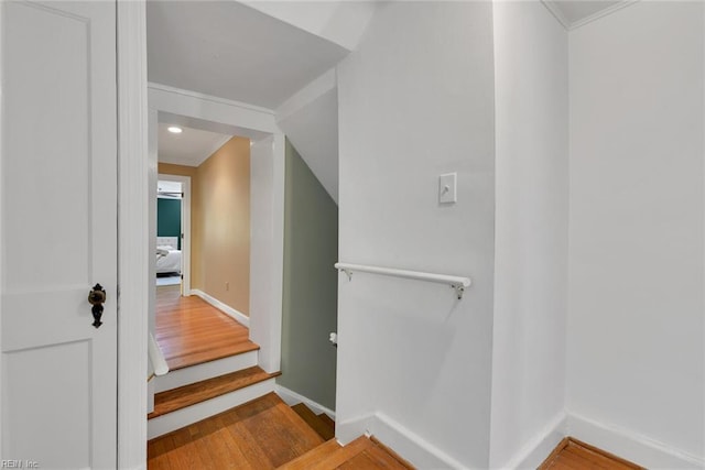 stairway with crown molding and hardwood / wood-style floors