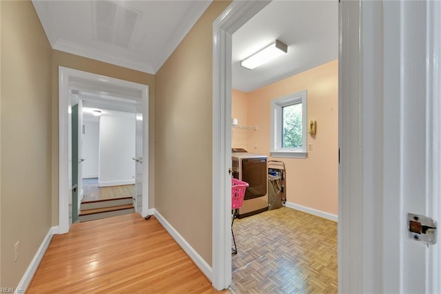 hallway with ornamental molding and washing machine and dryer