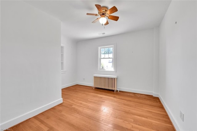 unfurnished room featuring radiator heating unit, light hardwood / wood-style floors, and ceiling fan