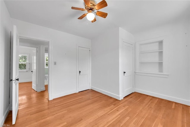 interior space with built in shelves, ceiling fan, and light wood-type flooring