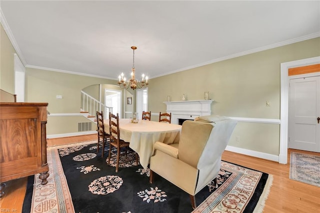 dining area with ornamental molding, an inviting chandelier, and light hardwood / wood-style flooring