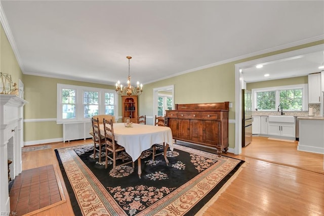 dining area with ornamental molding, a brick fireplace, radiator, and light hardwood / wood-style flooring