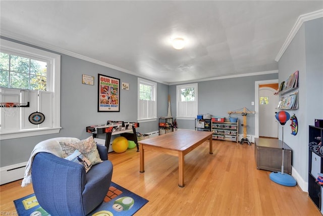 game room featuring crown molding, a healthy amount of sunlight, light hardwood / wood-style floors, and baseboard heating