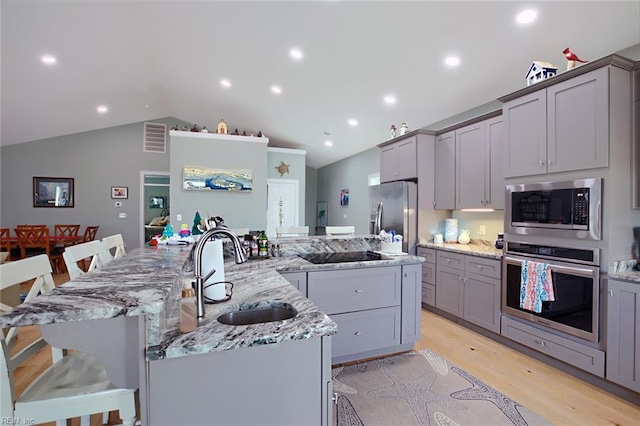 kitchen with appliances with stainless steel finishes, sink, a breakfast bar, and a spacious island