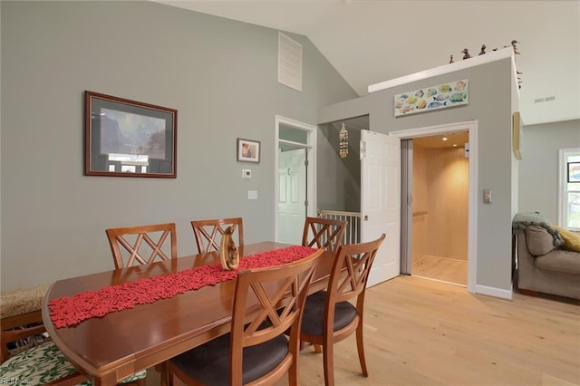 dining room with vaulted ceiling and light hardwood / wood-style floors