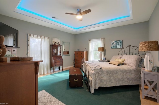 bedroom featuring light carpet, a raised ceiling, and ceiling fan