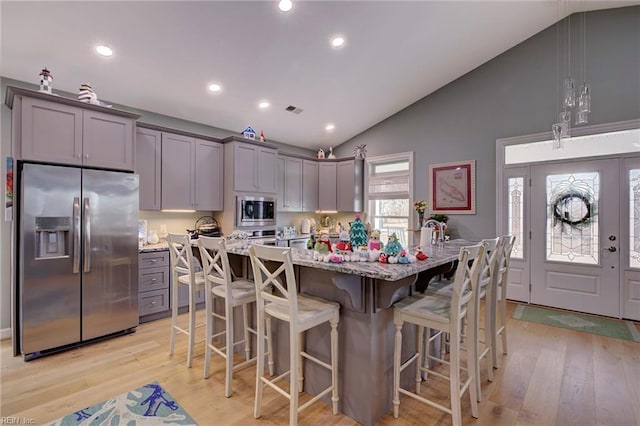 kitchen featuring gray cabinetry, a kitchen breakfast bar, an island with sink, stainless steel appliances, and light hardwood / wood-style floors