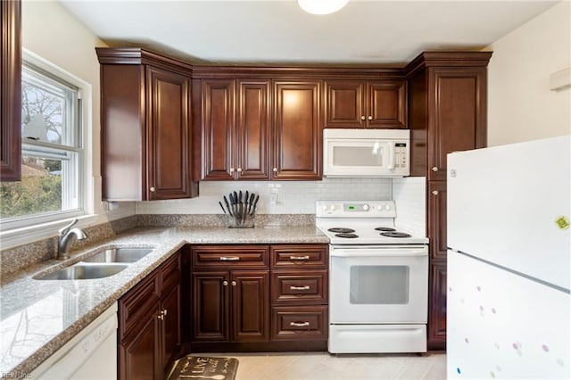 kitchen featuring light stone counters, white appliances, sink, and backsplash