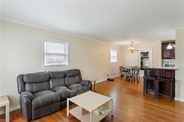 living room featuring crown molding, plenty of natural light, an inviting chandelier, and light hardwood / wood-style flooring