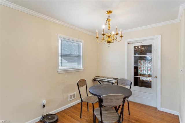 dining space with wood-type flooring, an inviting chandelier, and crown molding