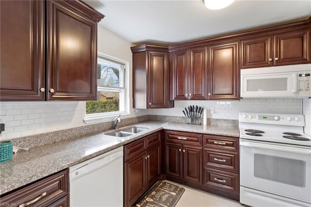 kitchen featuring light stone counters, white appliances, sink, and backsplash