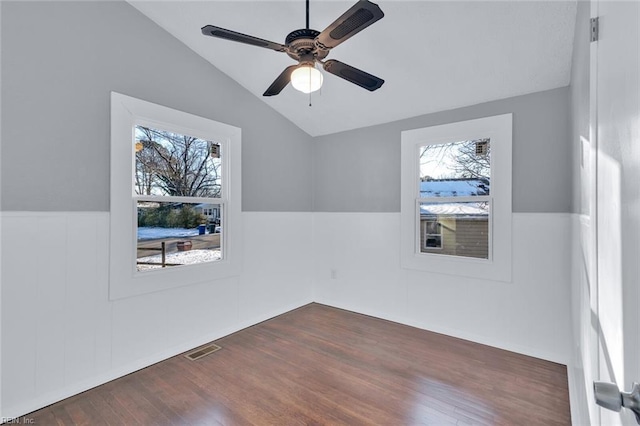 empty room with vaulted ceiling, plenty of natural light, dark wood-type flooring, and ceiling fan