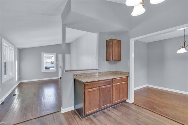 kitchen with an inviting chandelier, hardwood / wood-style floors, vaulted ceiling, and hanging light fixtures